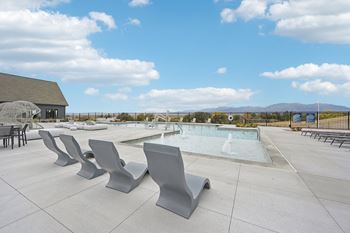 A pool surrounded by grey benches on a sunny day.
